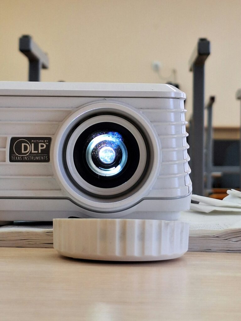 Best portable projector under £200 UK - white projector on wooden table