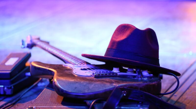 sinners film review blues guitar and hat on stage under purple light evoking 1930s Mississippi atmosphere