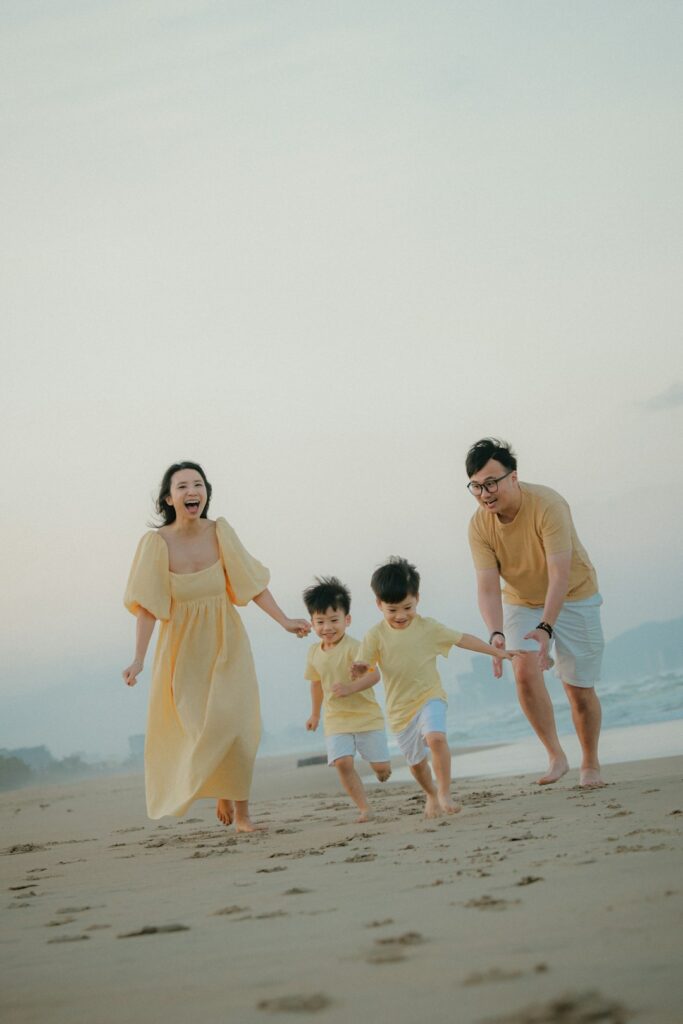 A family running happily on a sandy beach at sunset