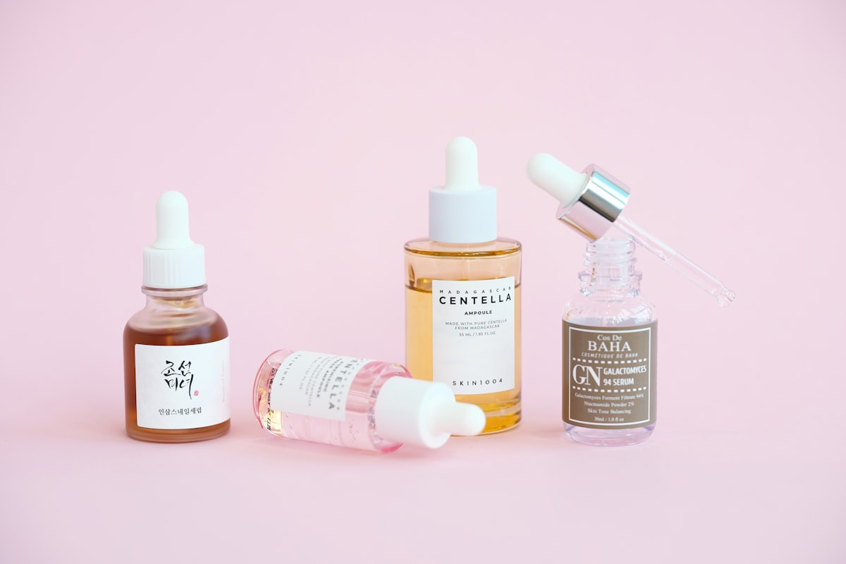 K-Beauty UK shelf of Korean skincare serums and bottles arranged on a pink background