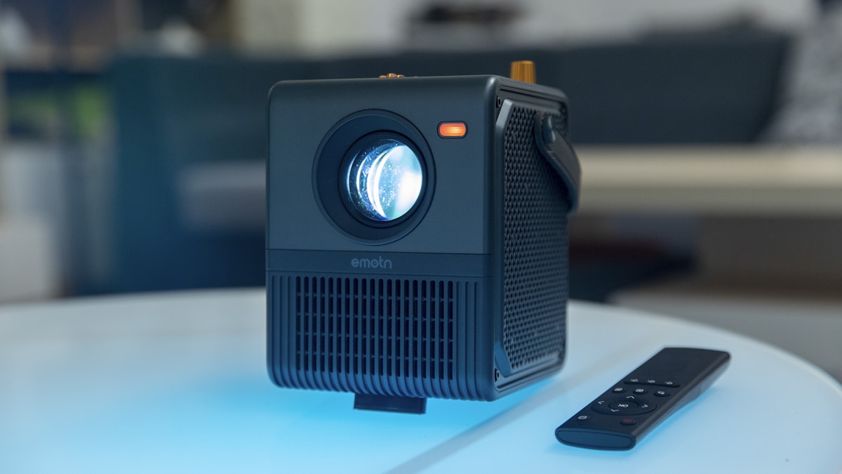 best portable projector under £200 UK - portable projector with remote control on table