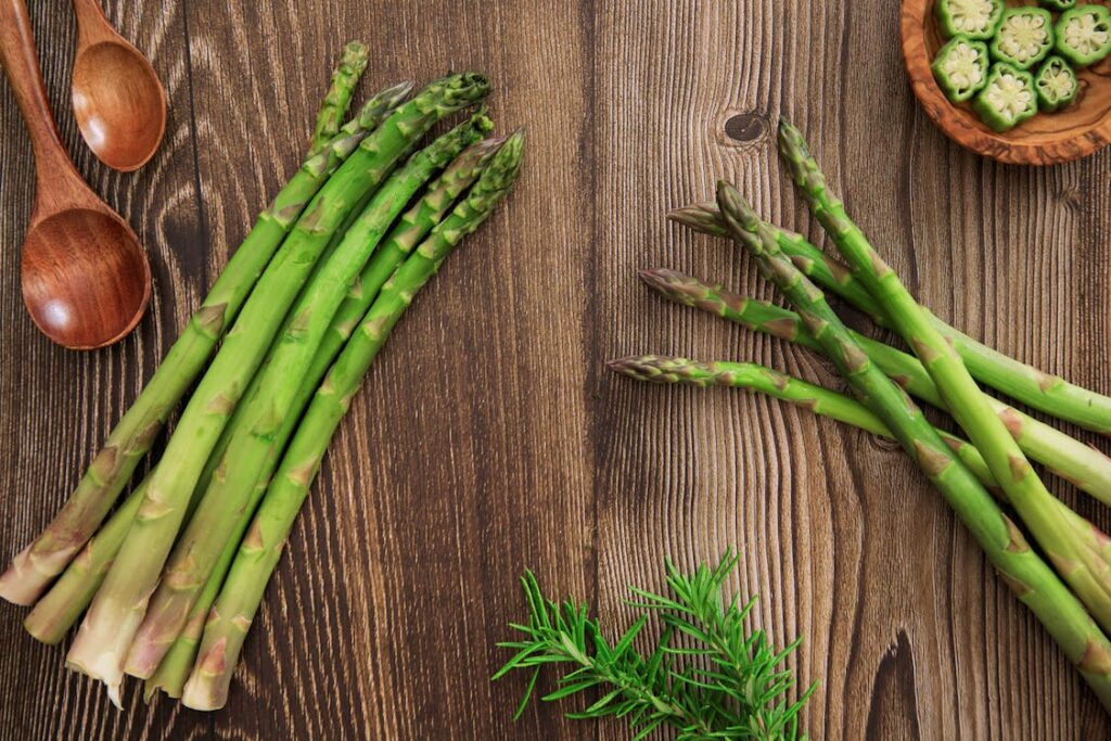 Fresh British asparagus spears arranged on a rustic wooden table with herbs and wooden spoons