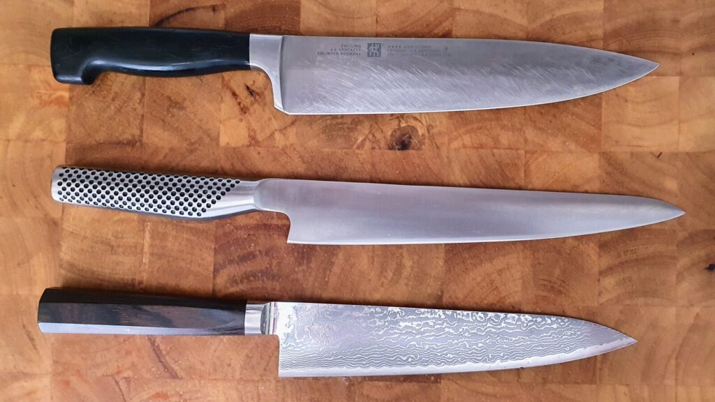 Row of chef knives on a wooden cutting board for our best chef knife UK 2026 buying guide.