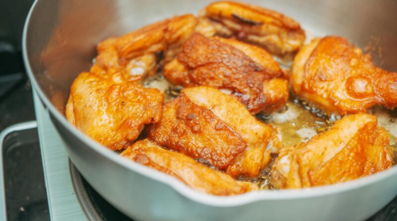 Chicken thigh recipes UK: bone-in chicken thighs frying skin-side down in a cast-iron pan.