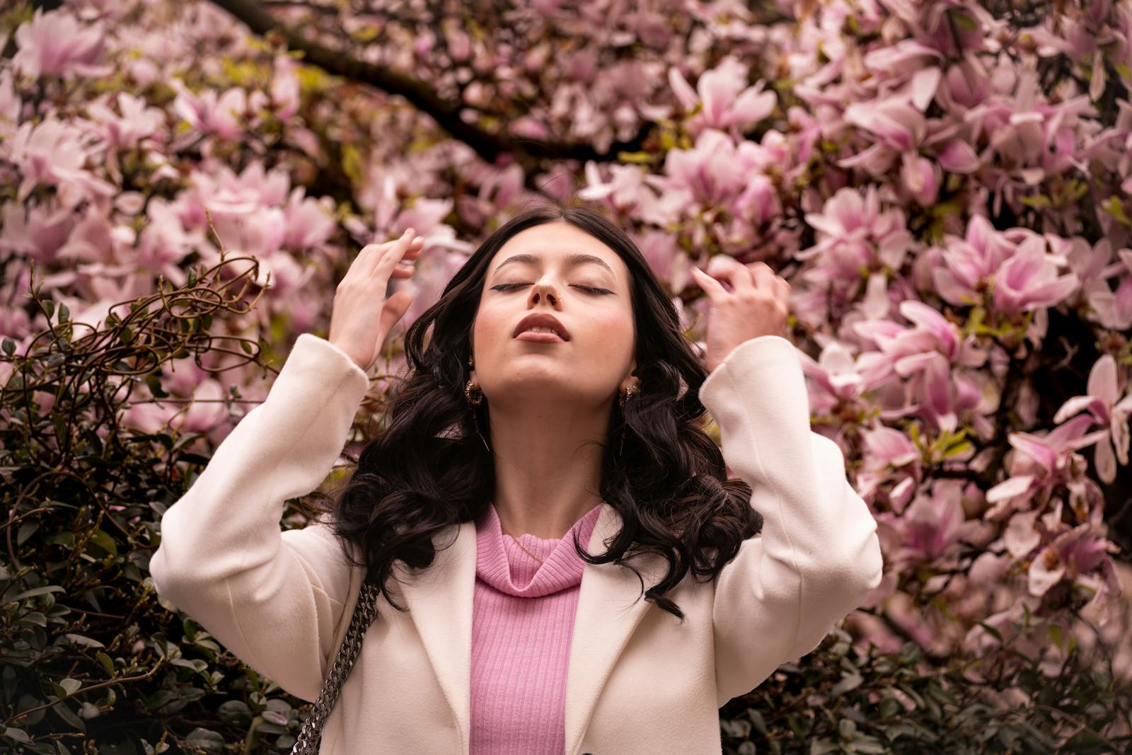Hay fever skin UK: a woman stands among blossoming trees on a sunny spring day, illustrating how pollen season drives reactive, flushed skin.