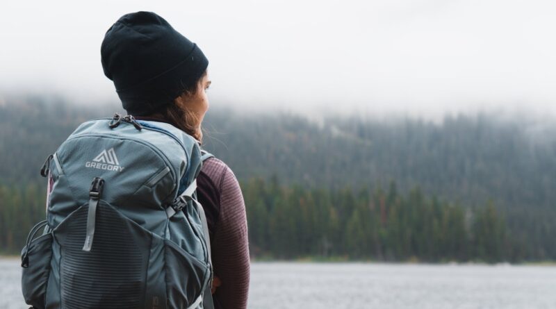 A woman with a backpack pauses by a misty UK lake on a rucking for women UK walk