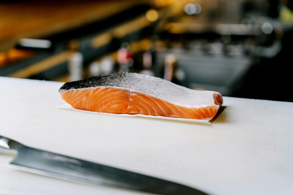 A fresh skin-on salmon fillet on a kitchen chopping board, ready for one of these salmon weeknight dinners UK home cooks rely on.