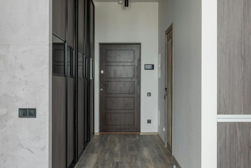 Modern hallway ideas UK 2026: a small entrance hall with built-in storage and a dark wood door.