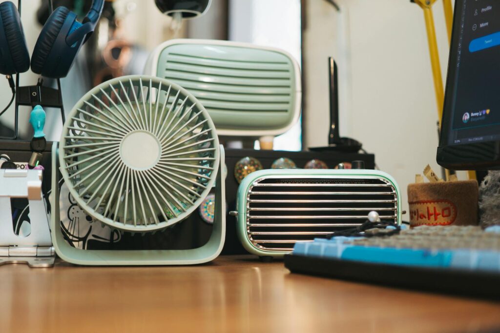 Small desk fan beside a monitor and keyboard, illustrating home office cooling UK setups for summer 2026.
