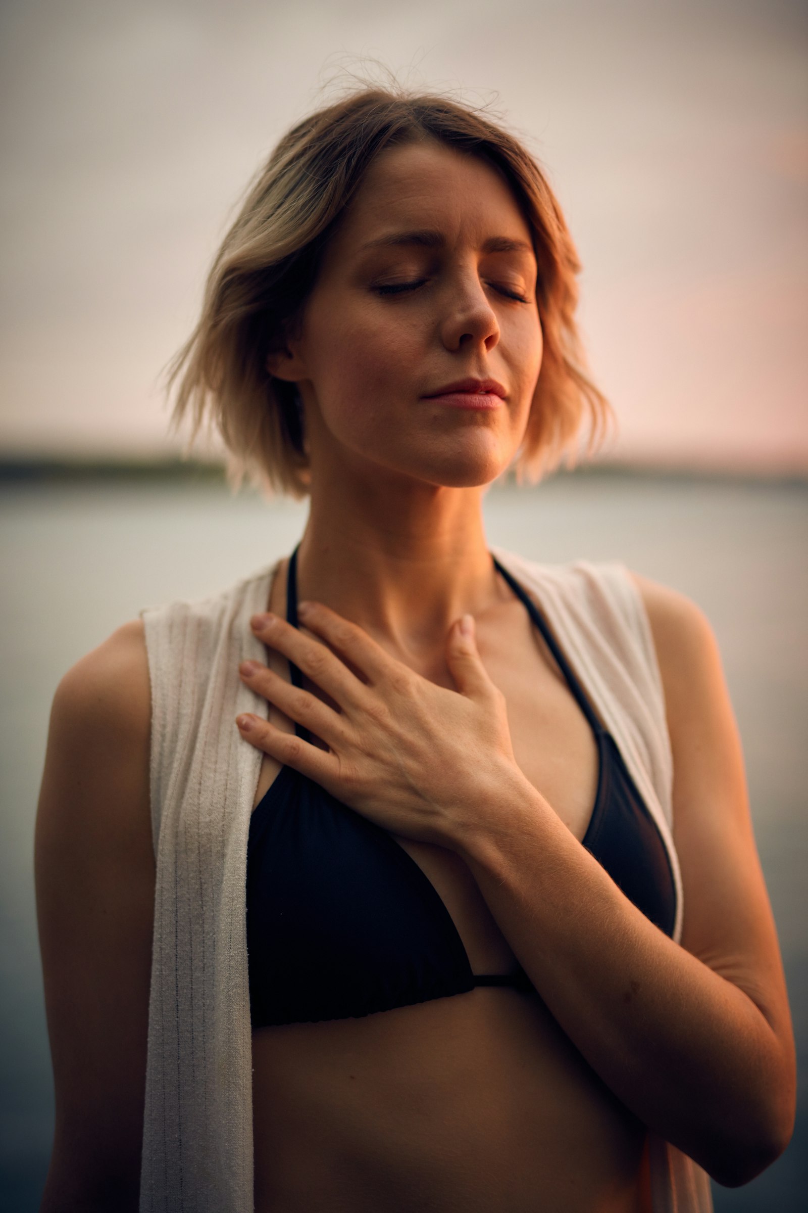 Woman with hand on chest practising slow breathing, illustrating the nasal-breathing rationale behind mouth taping