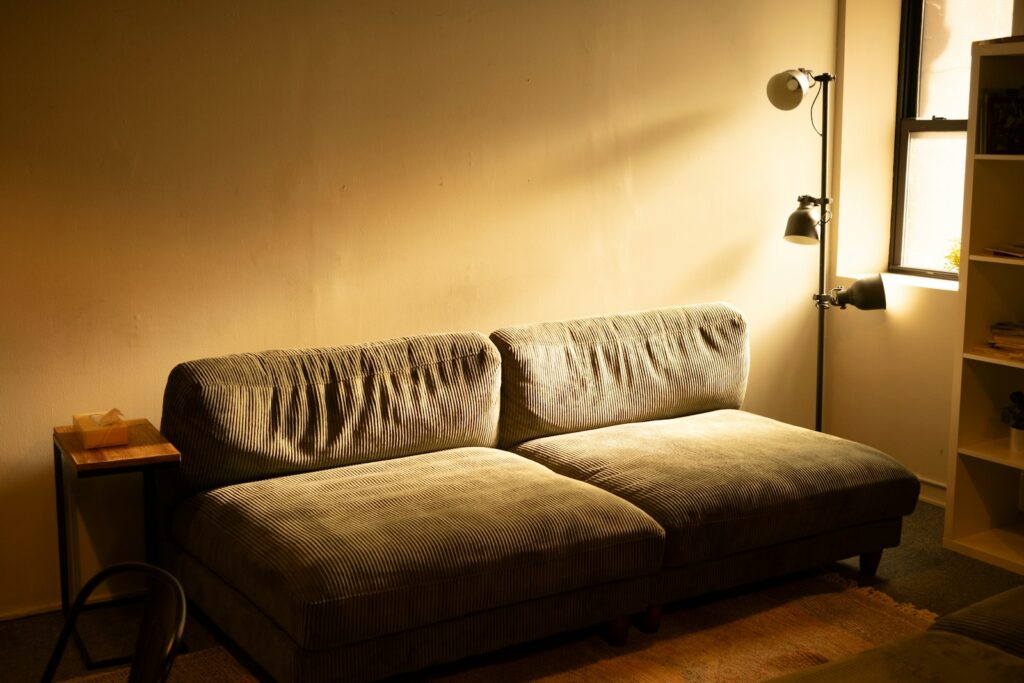 A warmly lit living room sofa under a single floor lamp, illustrating the no big light trend in UK homes in 2026.