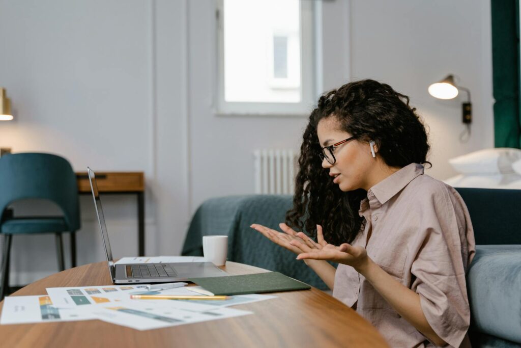 A UK home worker on a video call wearing earbuds at a home office desk - the case for an office headset UK home workers can rely on in 2026.