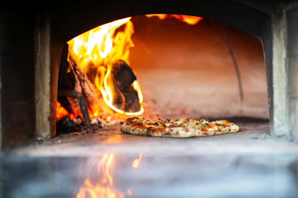 Outdoor pizza ovens UK guide: a wood-fired garden oven with bread baking inside.