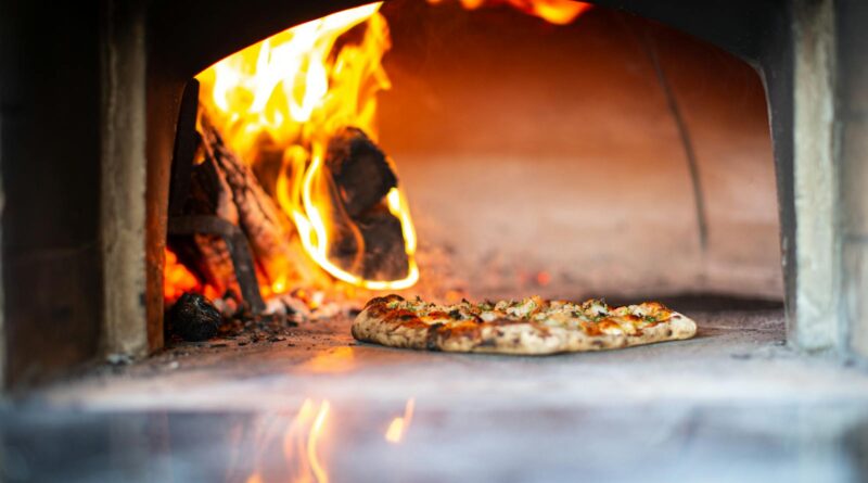 Outdoor pizza ovens UK guide: a wood-fired garden oven with bread baking inside.