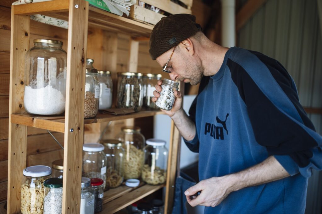 Someone organising jars on the shelves of a small kitchen, illustrating practical small kitchen storage ideas.