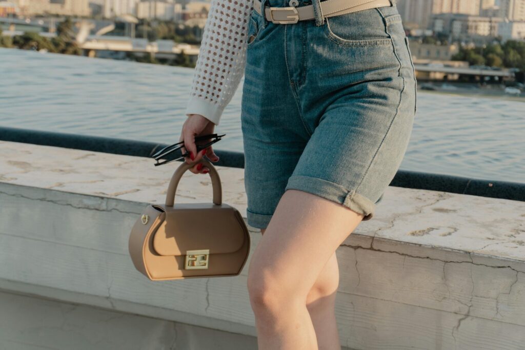 Woman wearing tailored shorts and carrying a structured handbag on a sunny summer day, showing how tailored shorts work as a polished warm-weather outfit.