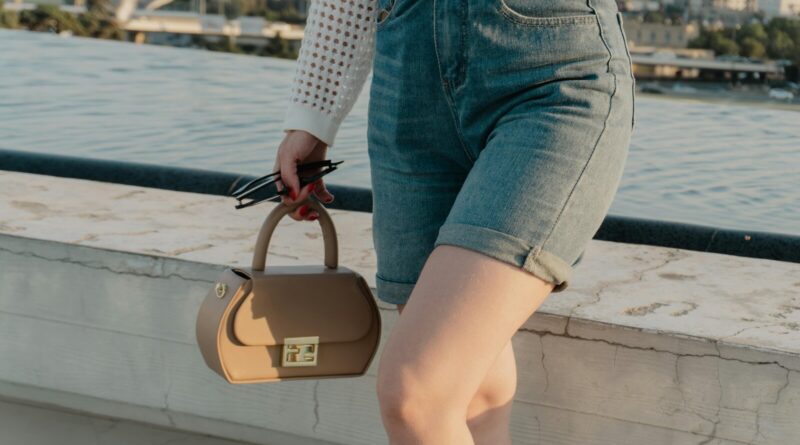 Woman wearing tailored shorts and carrying a structured handbag on a sunny summer day, showing how tailored shorts work as a polished warm-weather outfit.