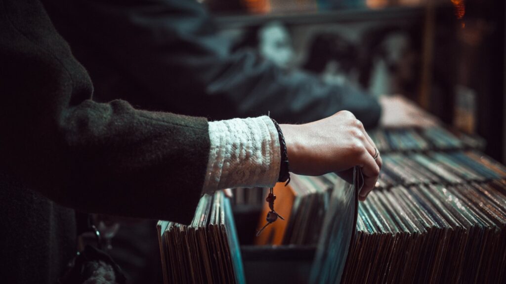 A record-store browser flicking through LP sleeves, illustrating UK vinyl sales 2026.