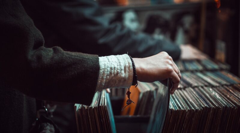 A record-store browser flicking through LP sleeves, illustrating UK vinyl sales 2026.
