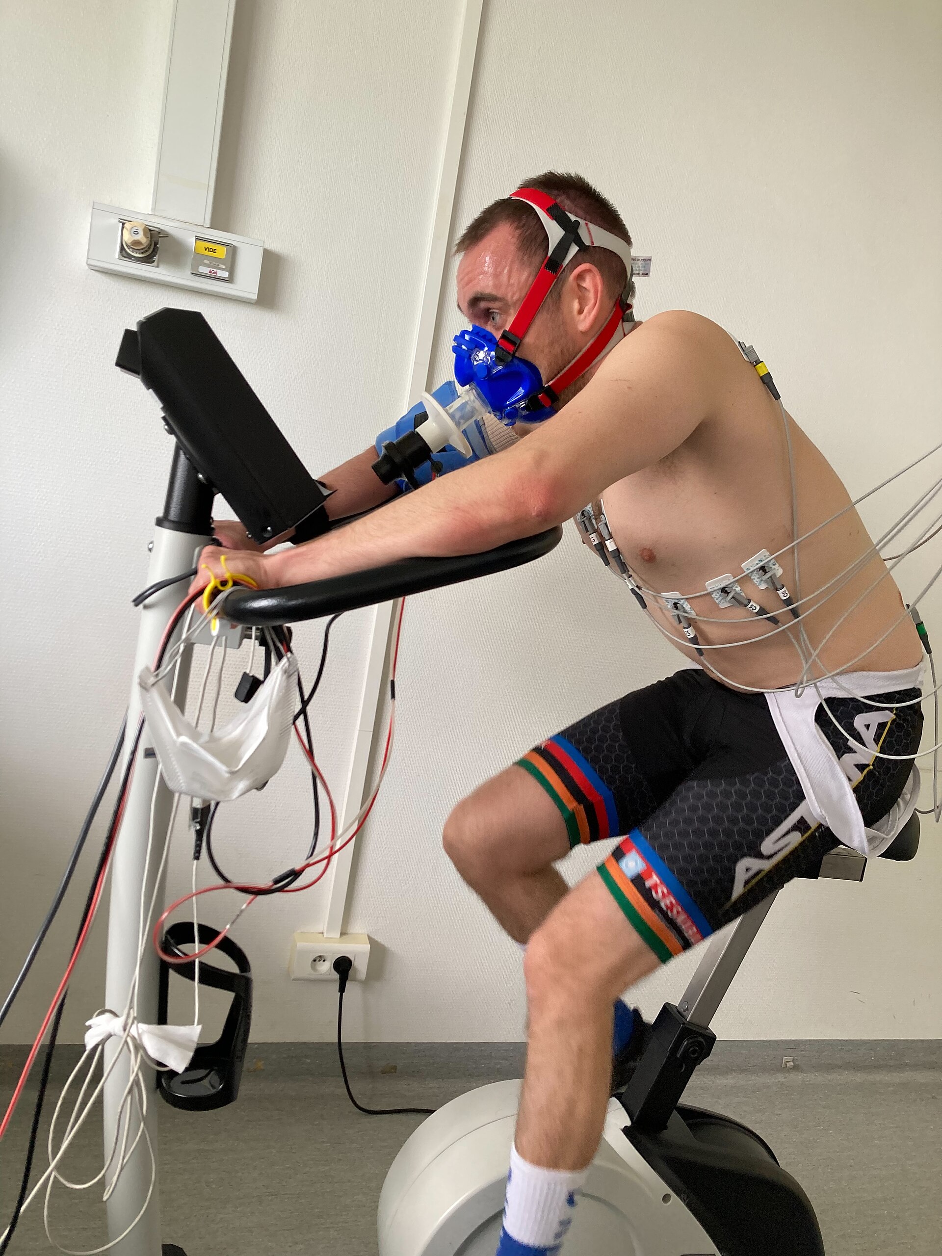 A subject undergoing a VO2 max test in a sports science lab, wearing a gas-exchange mask on a treadmill