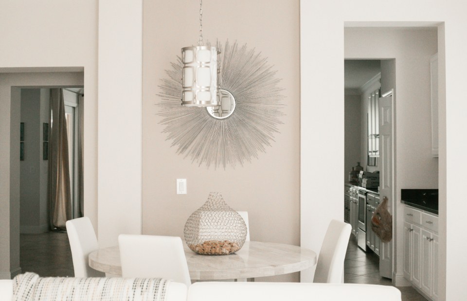 Light dining nook with a round table, pendant light and starburst mirror