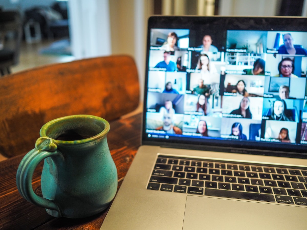 A laptop video call in a dim home office lit mostly by the screen