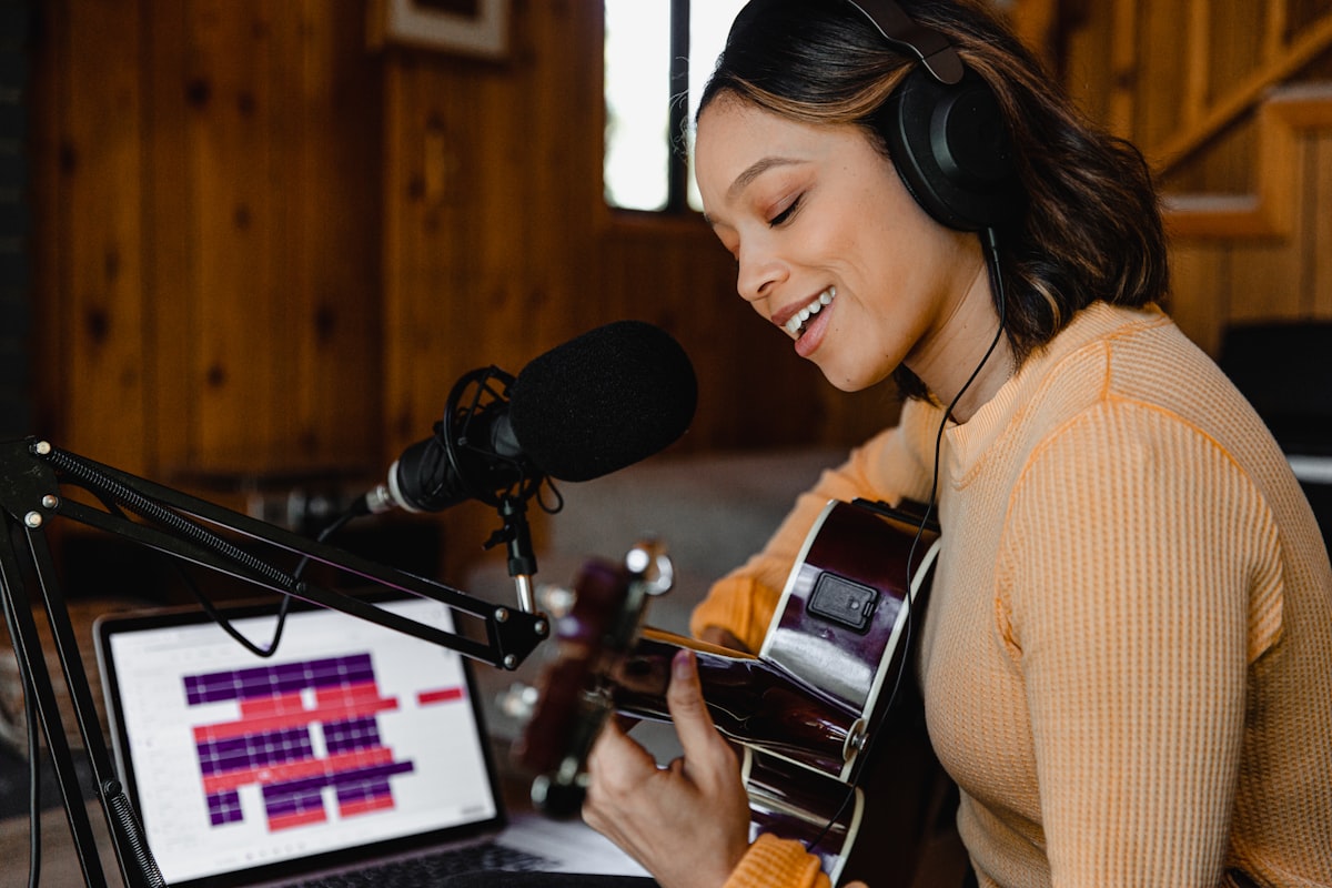 Home worker speaking into a microphone with headphones on and audio software on screen