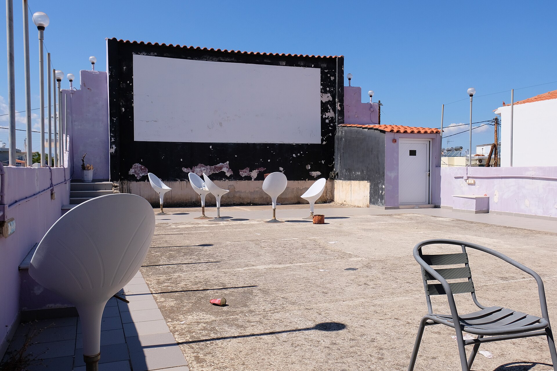 An open-air cinema audience watching a film on a large screen at dusk