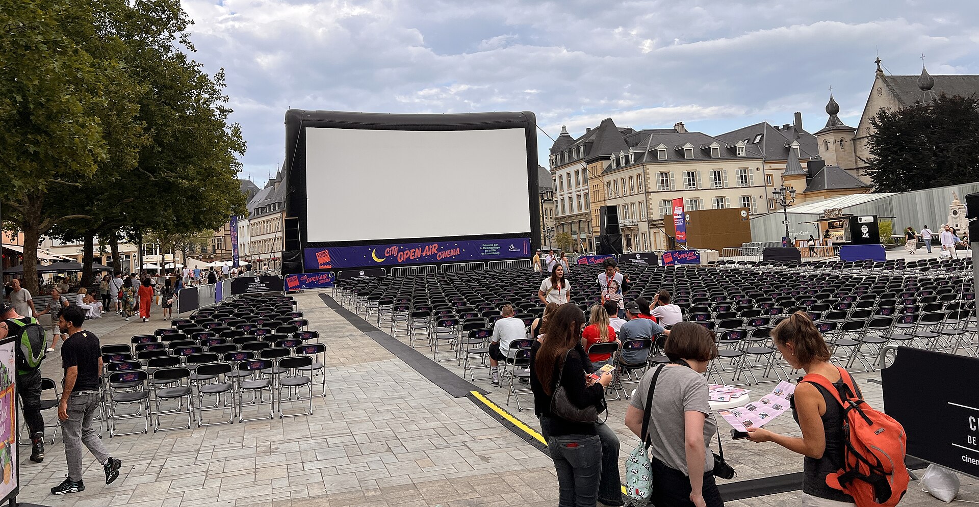 Outdoor cinema 2026: a large open-air screen lit up in a city square at night