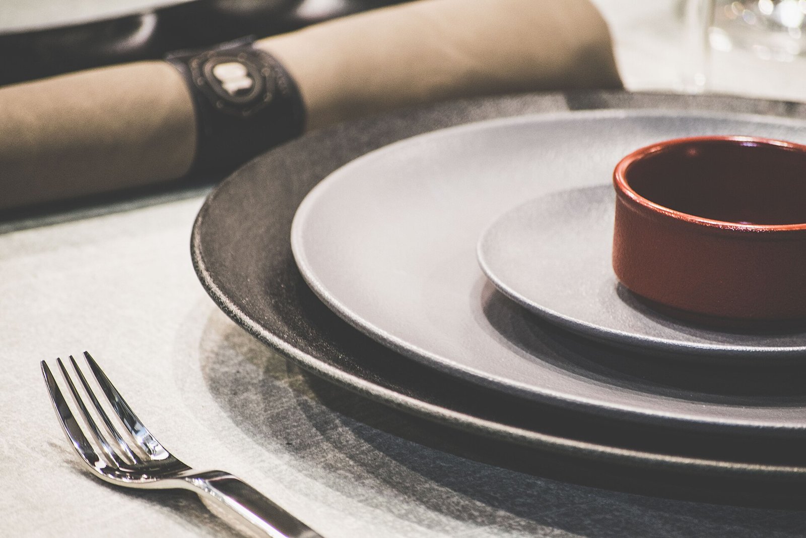 A modern tablescaping place setting with layered plates and linen on a dining table