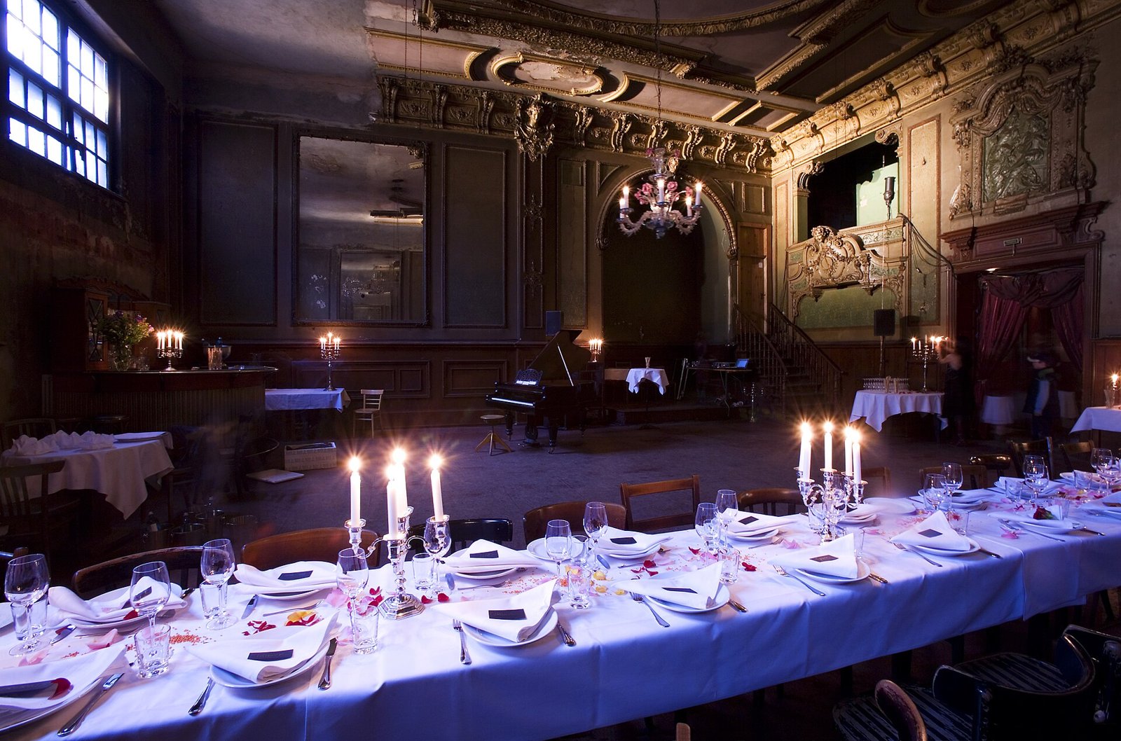 A laid dinner table dressed for a tablescaping dinner party with candles, glasses and linen