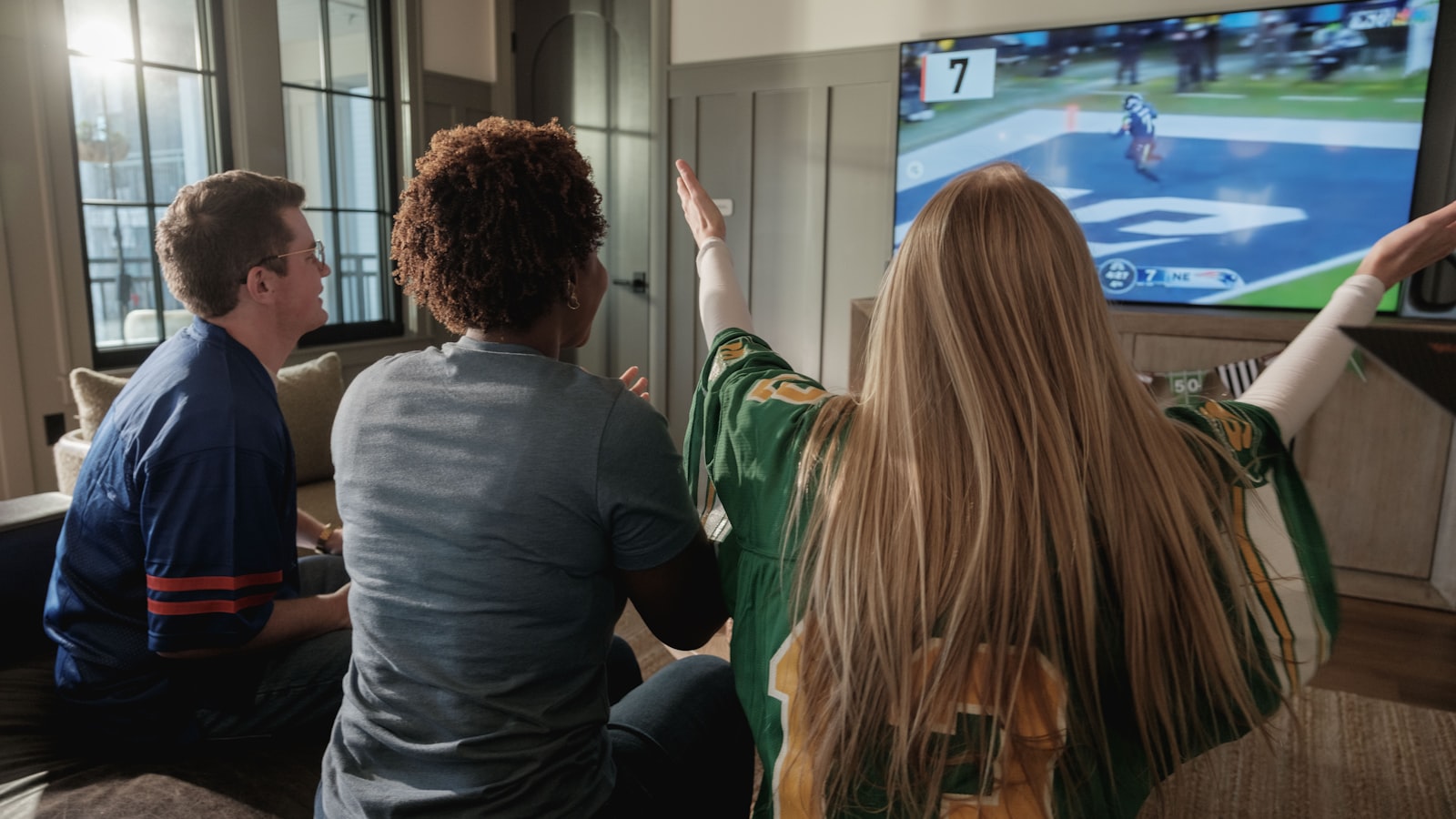 Friends watching a football match together on the sofa at home