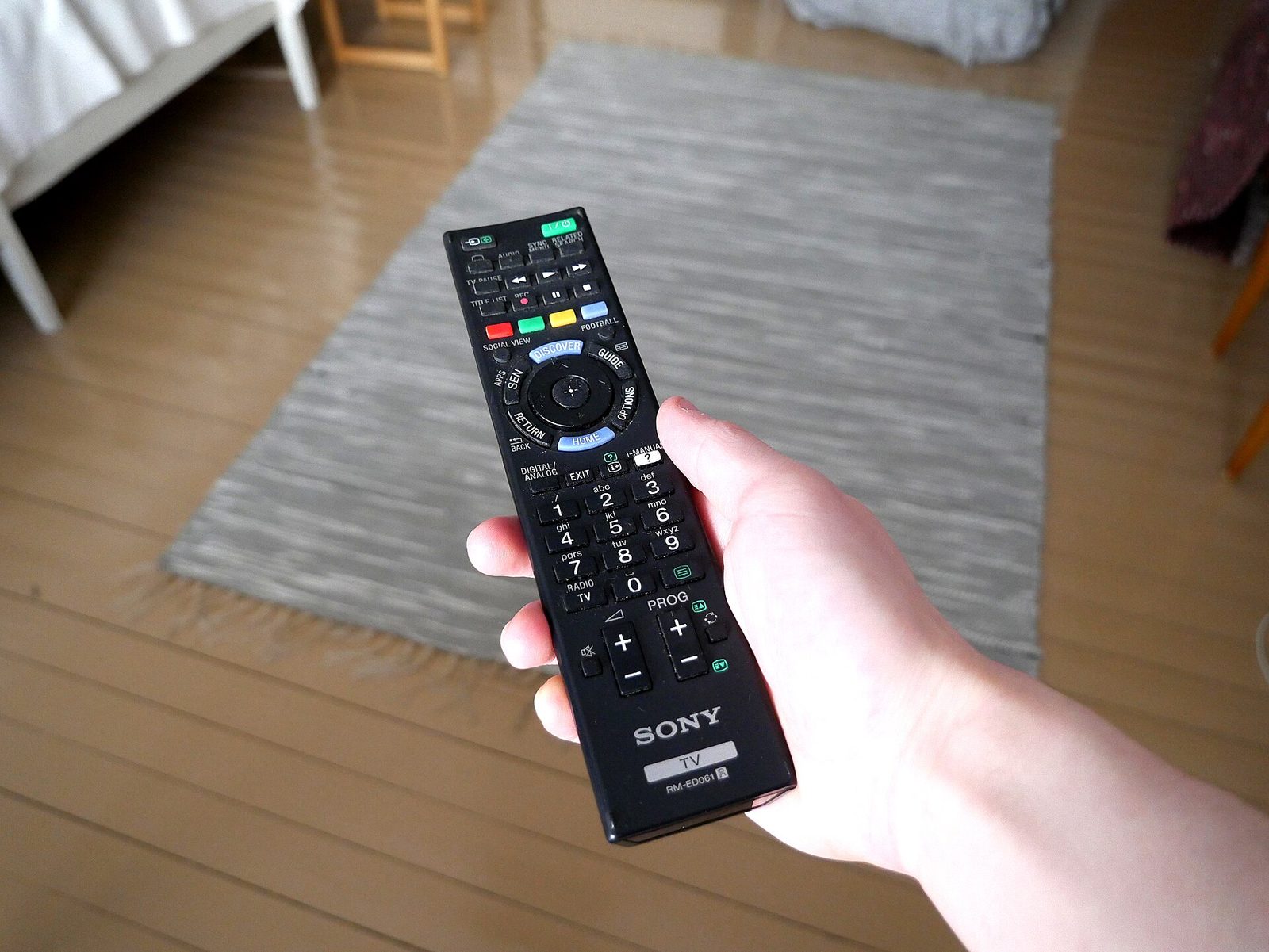A hand reaching for the remote control to turn subtitles on while watching TV