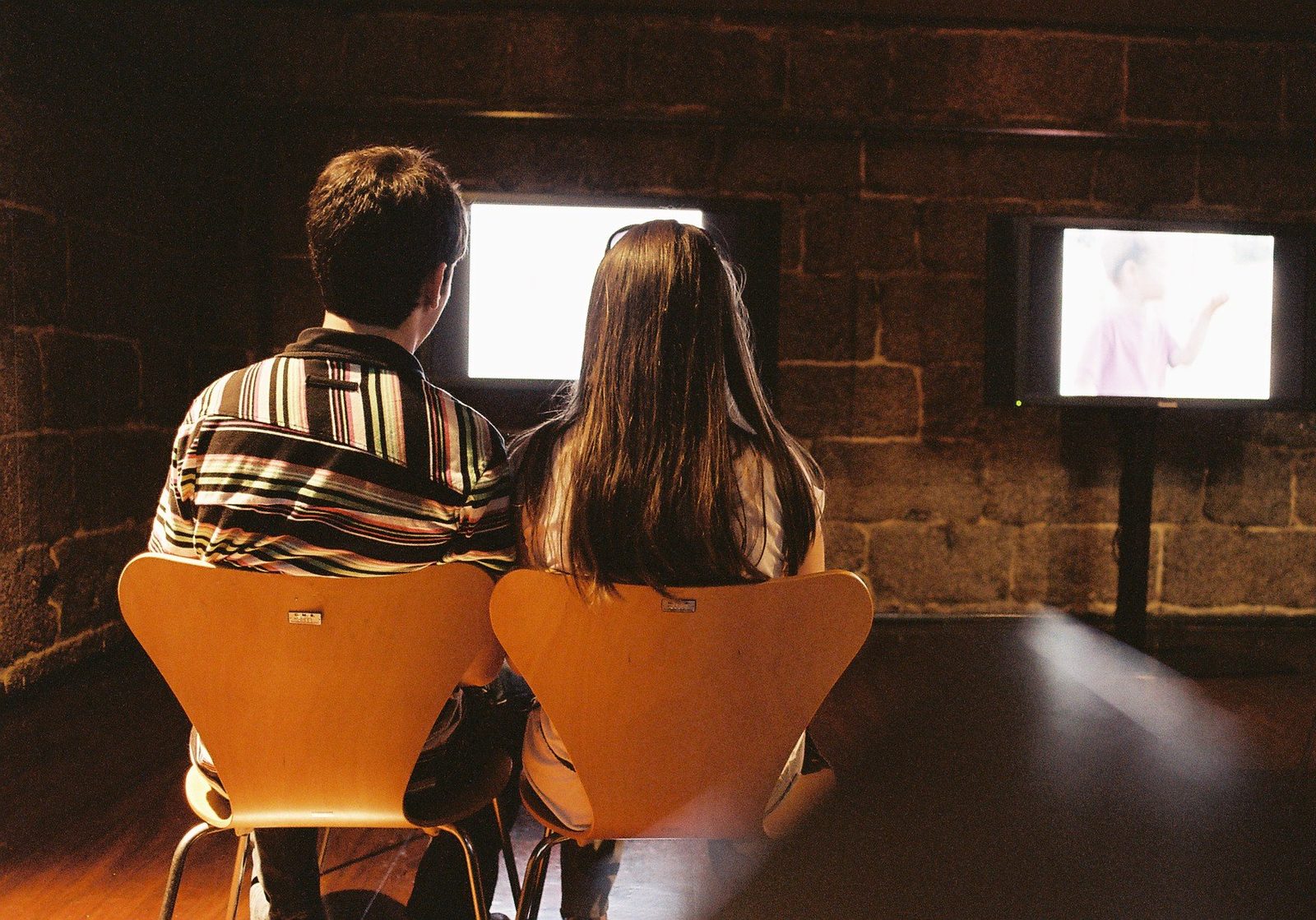 Two people watching TV with subtitles running along the bottom of the screen