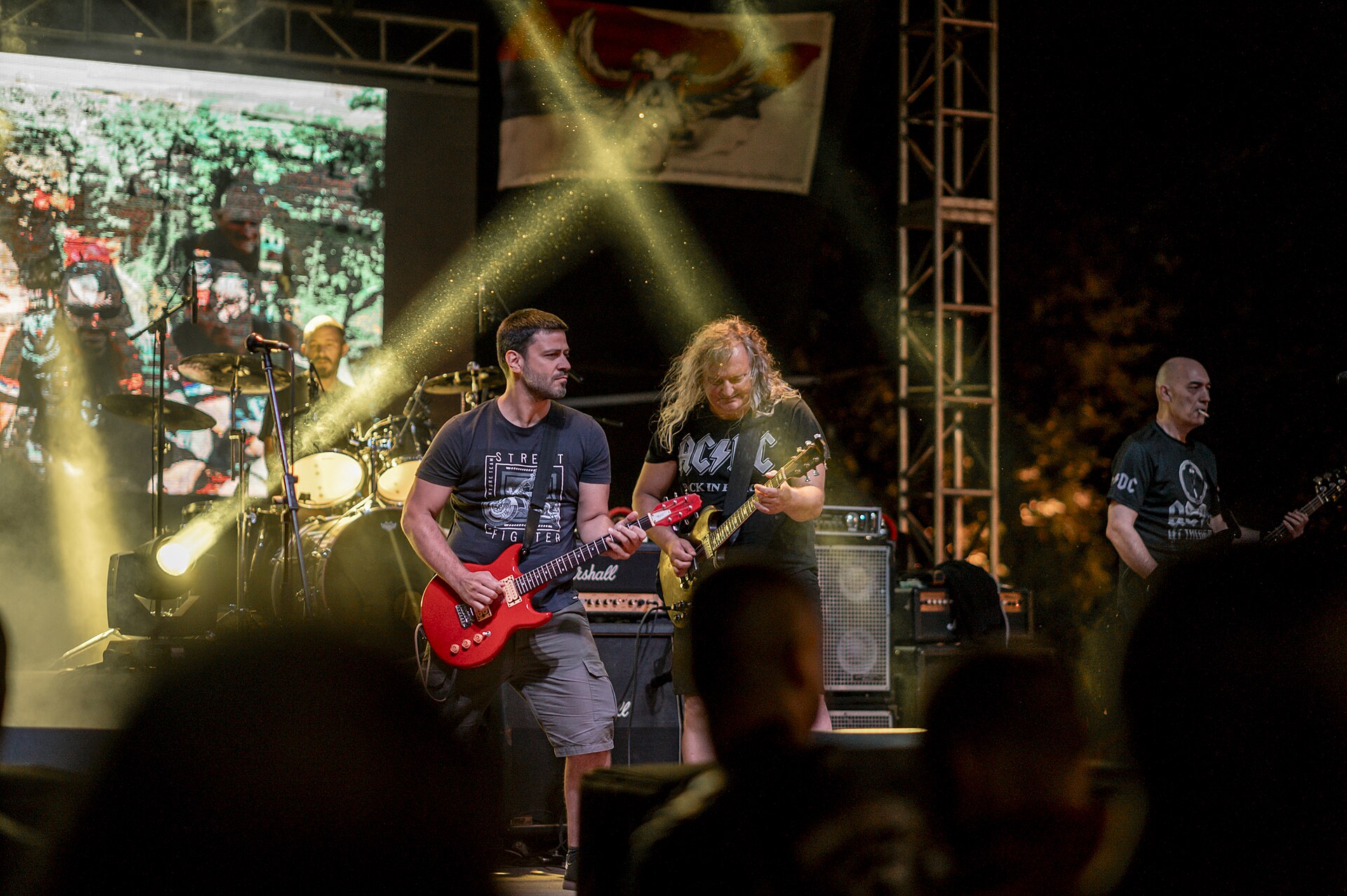 A live rock concert with guitarists on stage under coloured lights