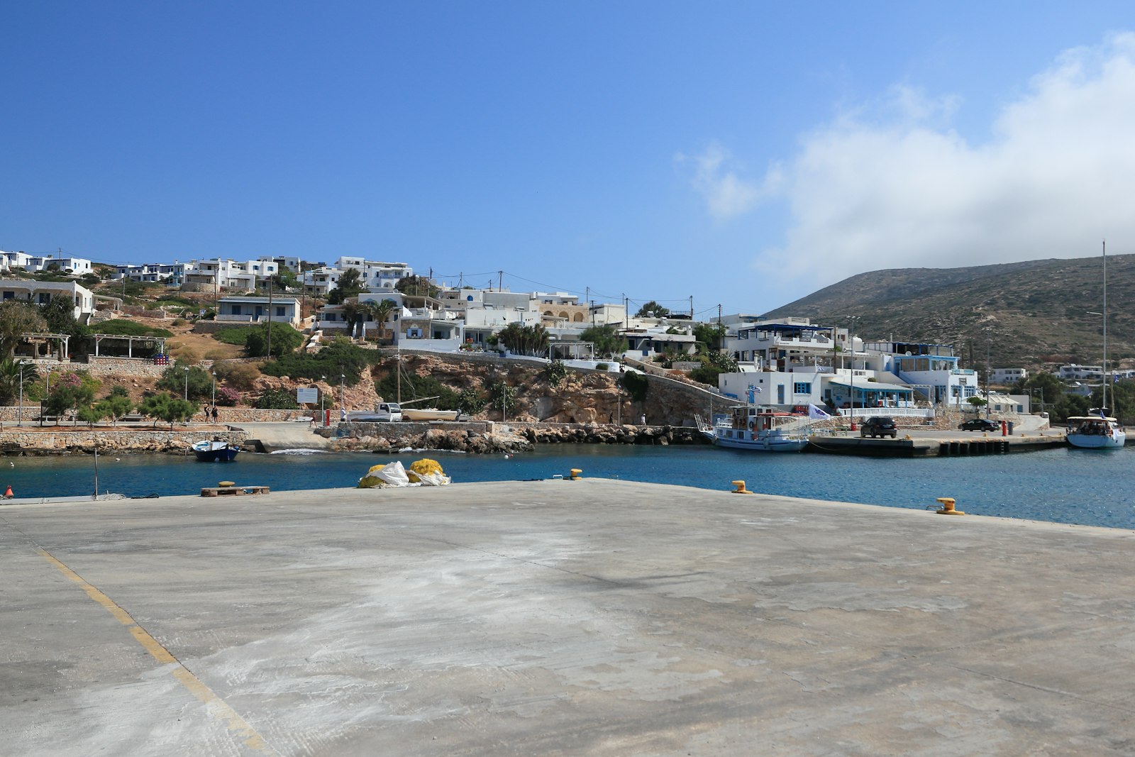 Whitewashed buildings above the sea on a Greek island, the setting that shapes Two Weeks in August