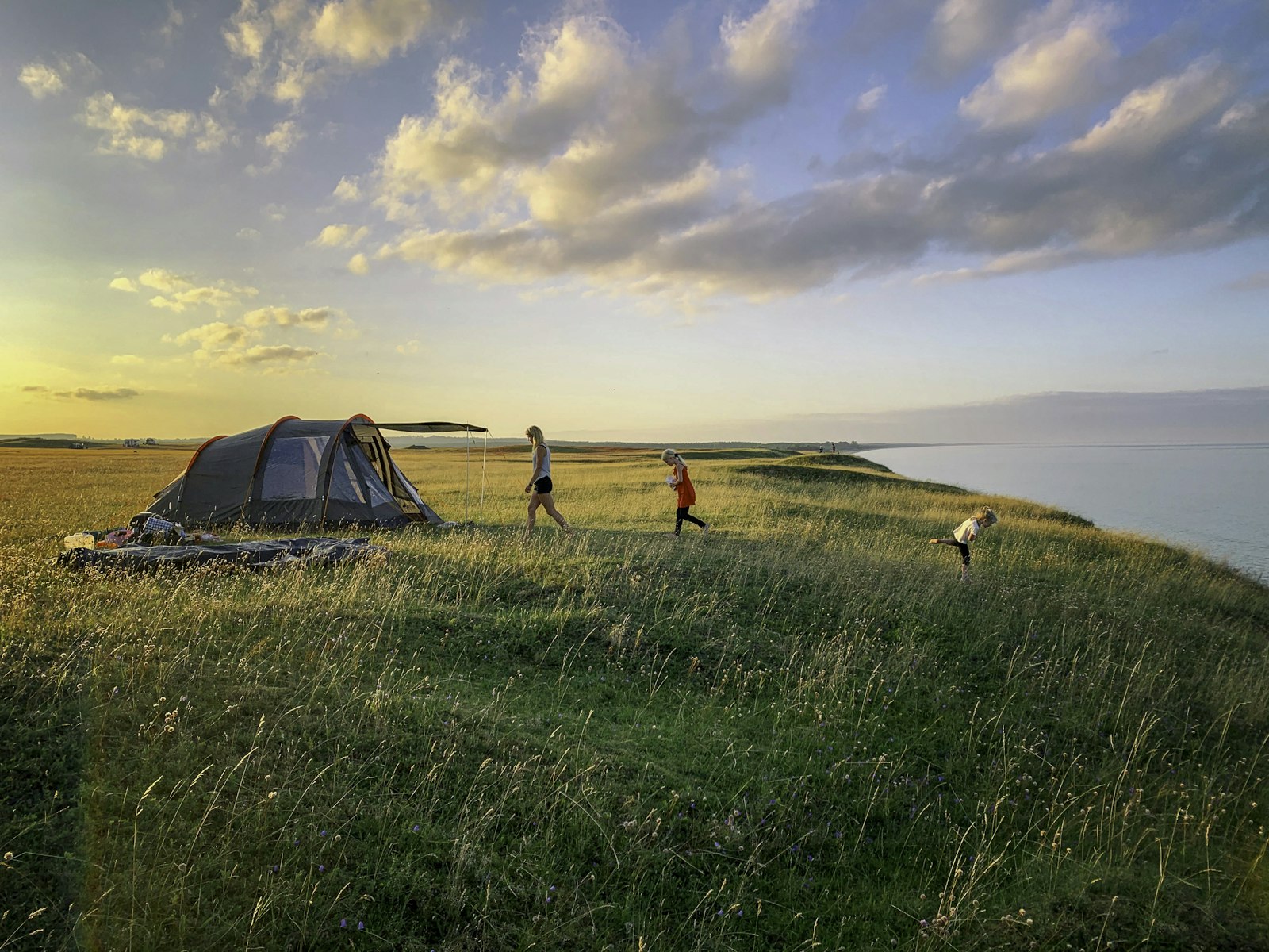 Family tent pitched on a grass campsite at golden hour in a British summer