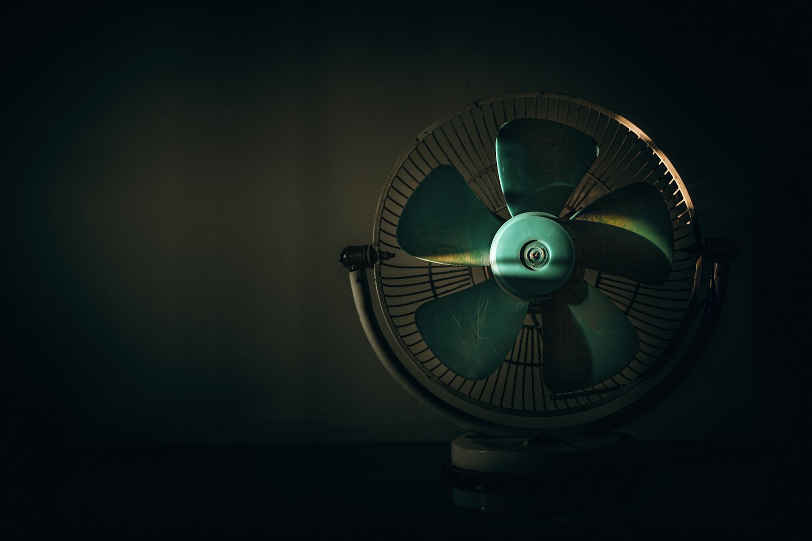 Compact desk fan on a bedside table in a warm room