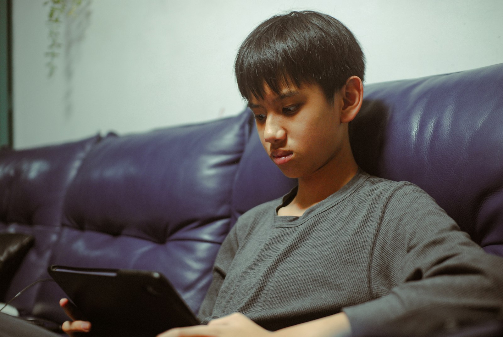 Boy watching a downloaded film on a kids tablet on the sofa