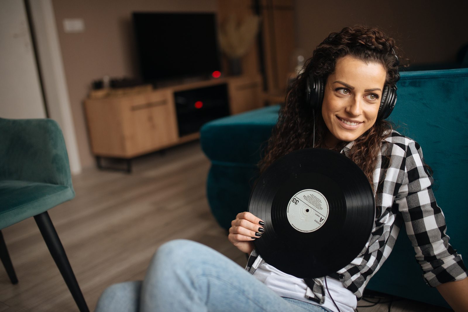 A woman listening through headphones on a sofa at home in the afternoon