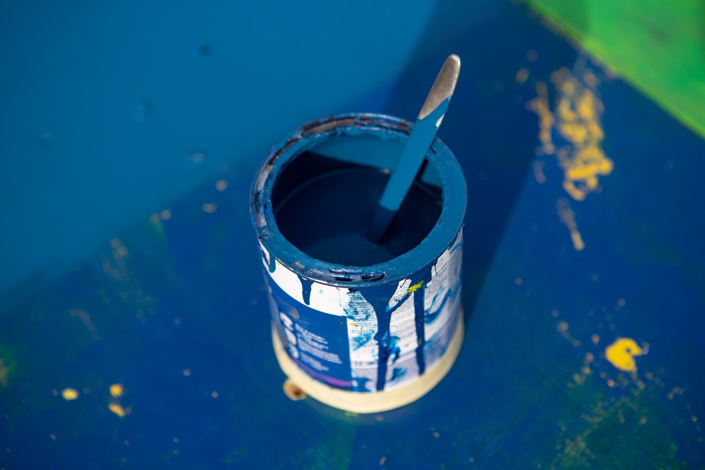 Open tin of blue paint with a loaded brush resting on the rim