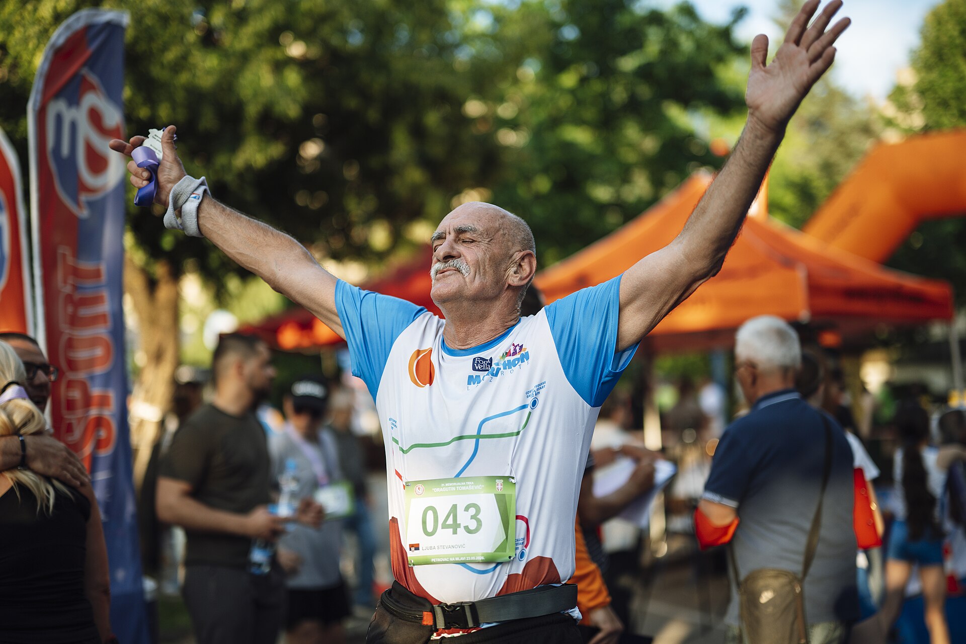 Older runner celebrating at the finish of a summer running event in a UK park