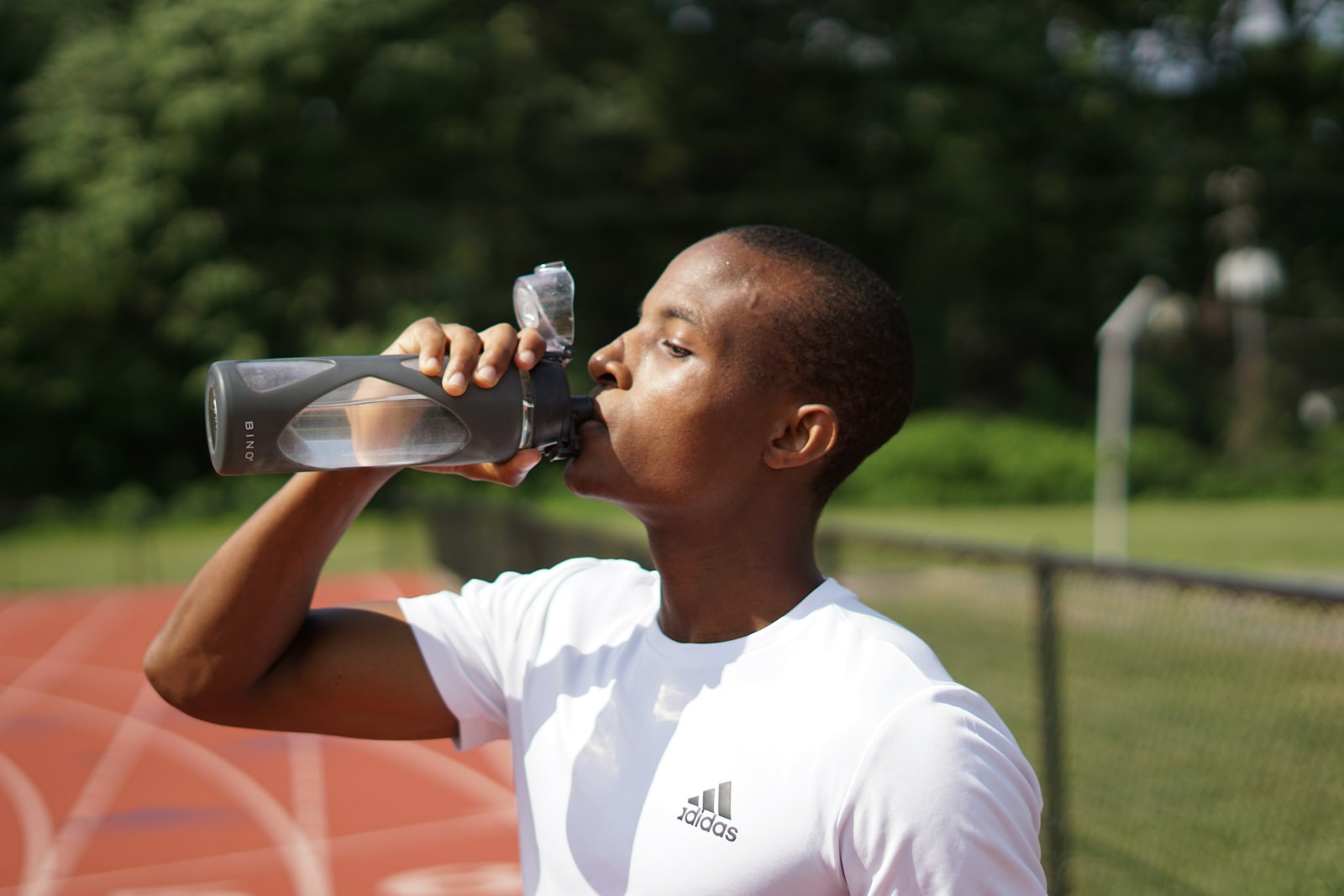 A person drinking water from a sports bottle while exercising in a heatwave
