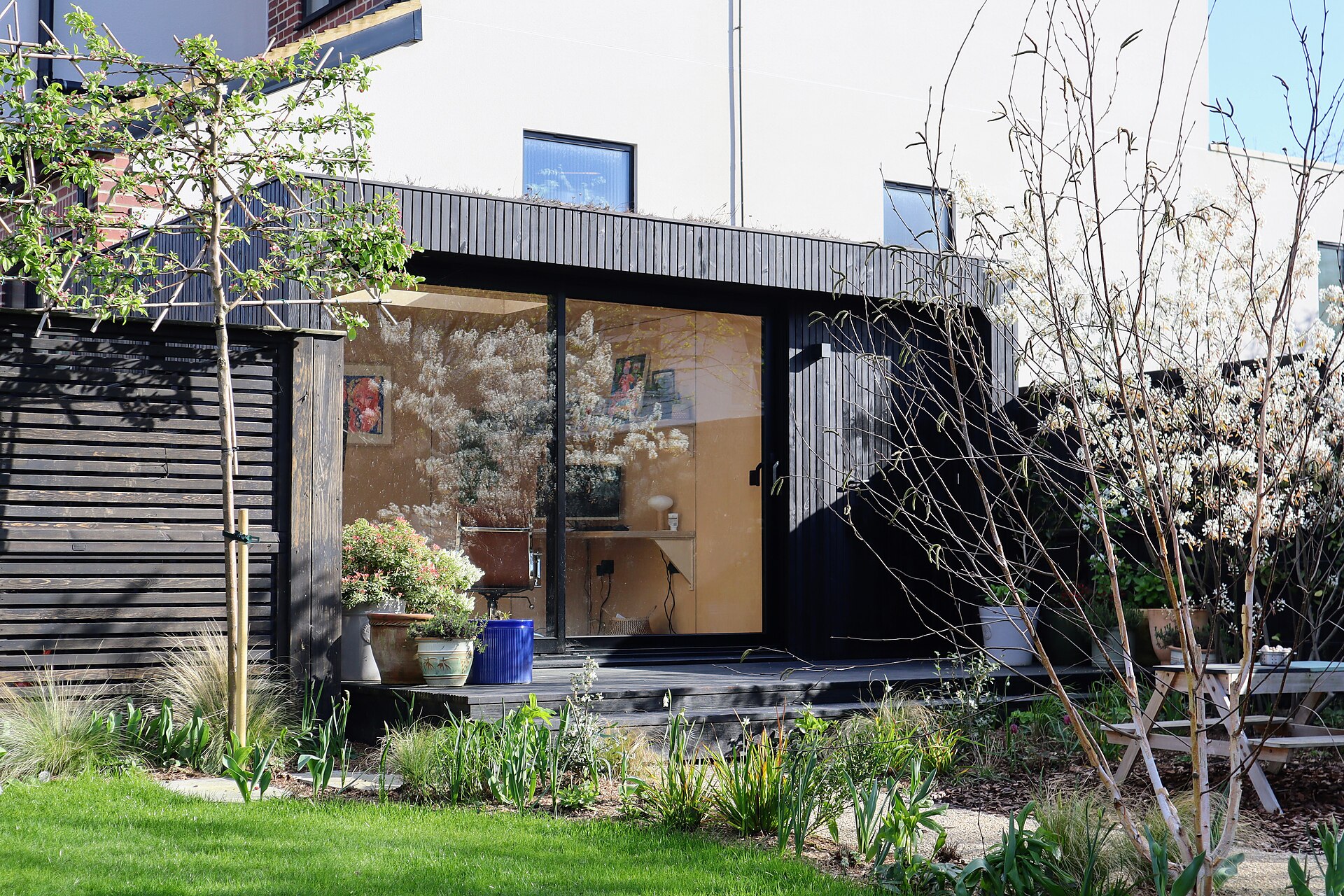 Modern insulated garden room in a UK garden with charred timber cladding