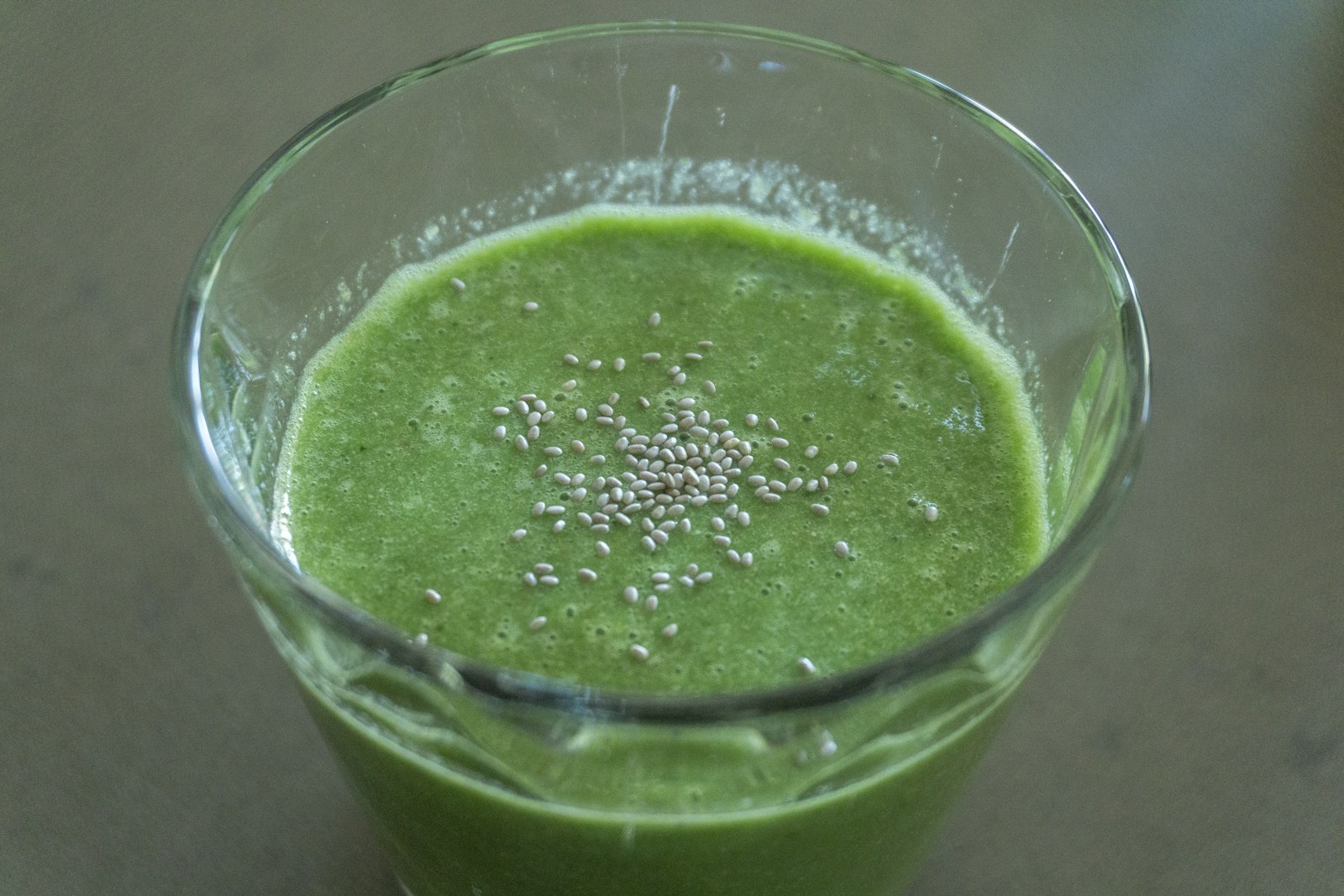 A glass of green drink mixed from greens powders on a kitchen counter