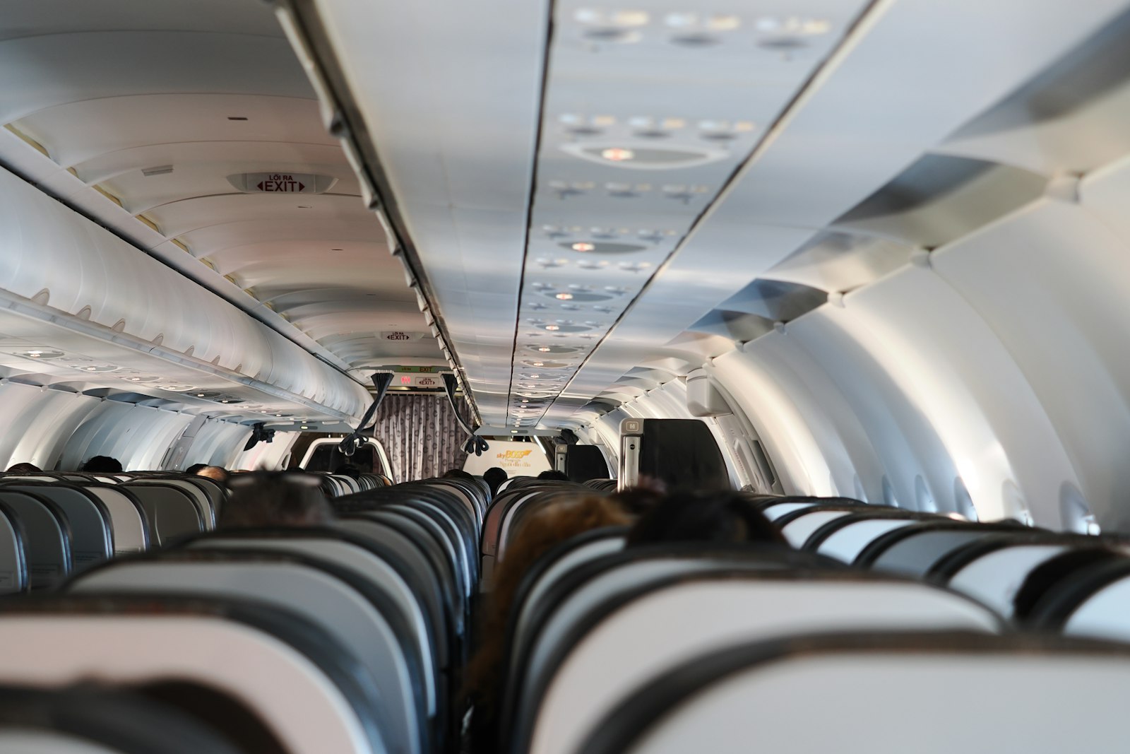 Passengers seated in an airplane cabin after stowing hand luggage