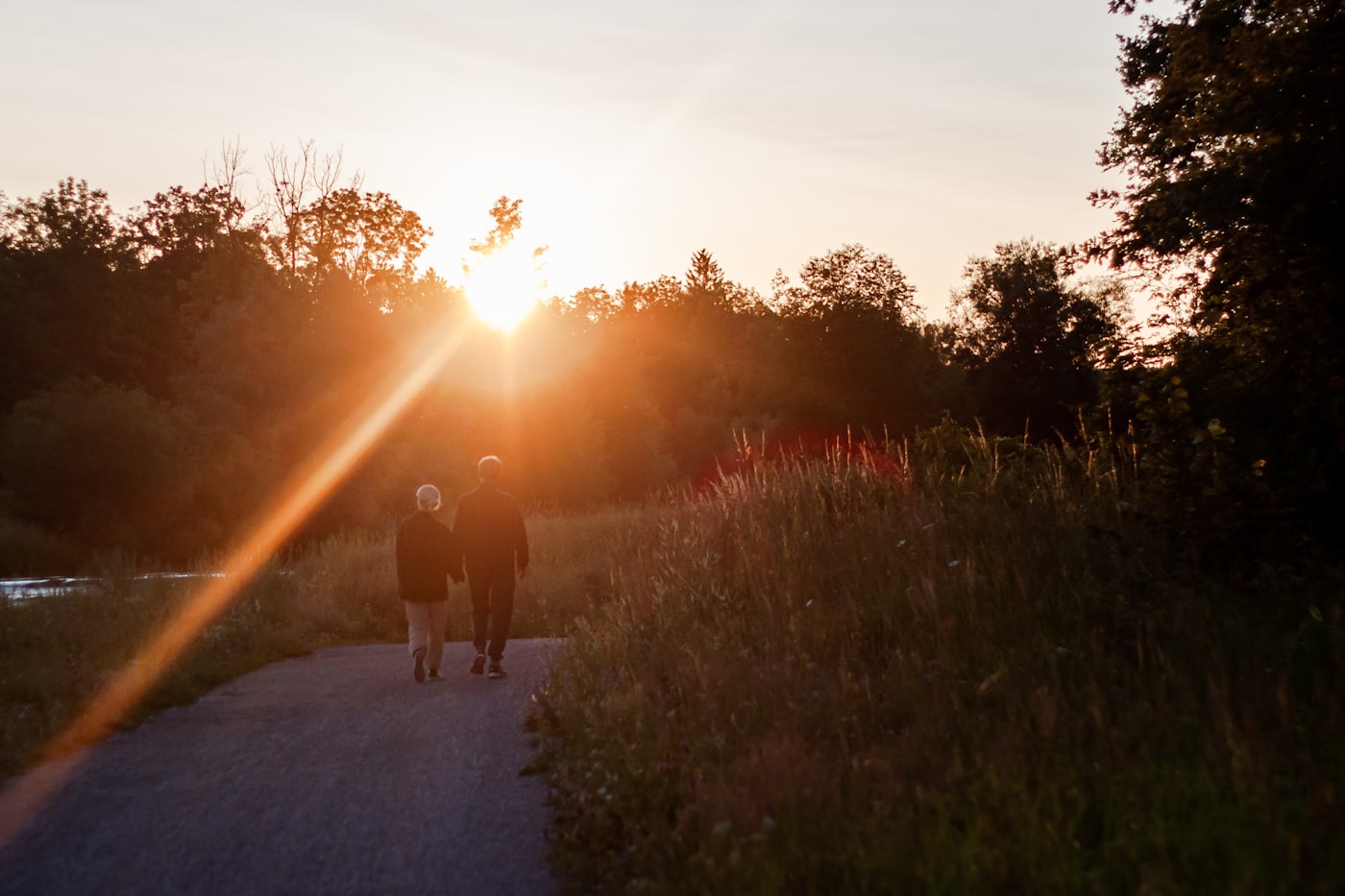 Older couple walking briskly on a countryside path in evening light