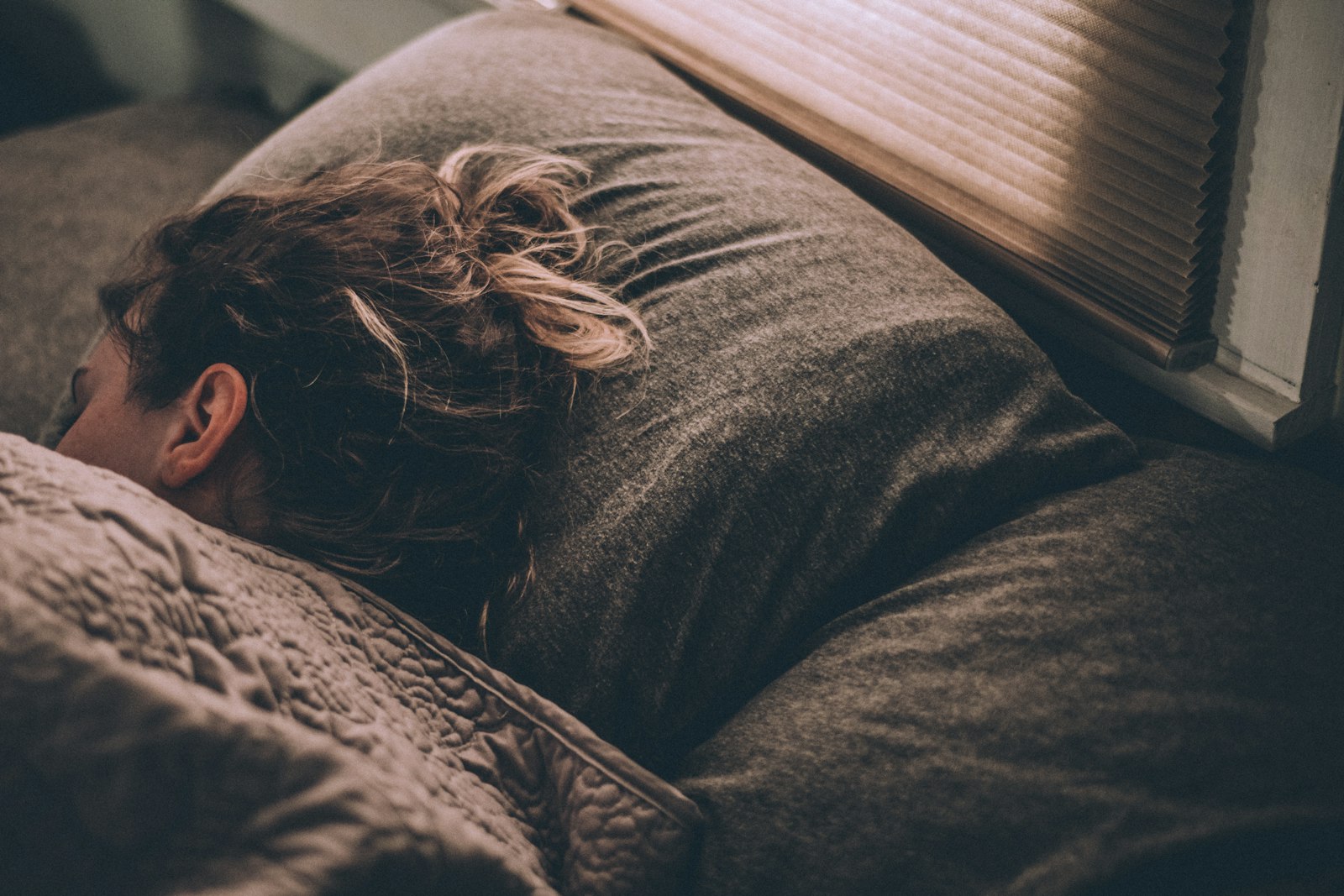 Woman asleep under a duvet - magnesium for sleep has become one of Britain's most searched supplement questions