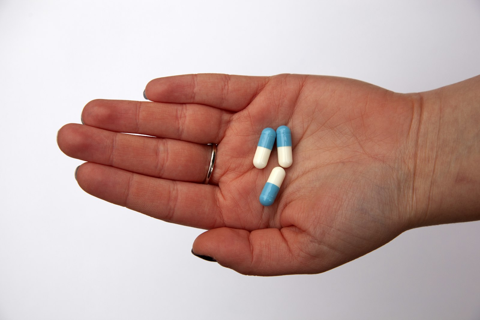 Three supplement capsules held in an open palm
