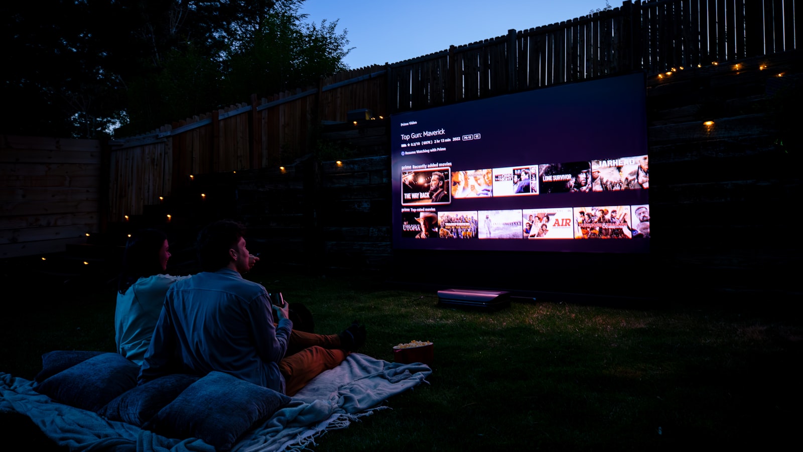 Two people watching a film from a blanket at an open-air screening